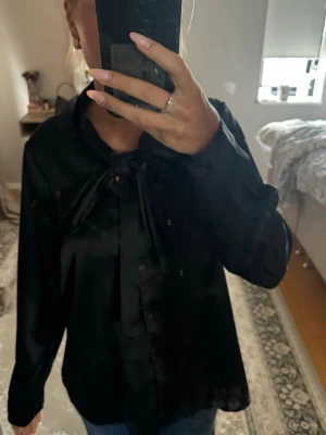 Svart sidenblus med knytband - Siden blus i storlek 38/40 ifrån märket Cellbes, jätte fin och man kan även dölja dessa knytband som är vid halsen under blusen.