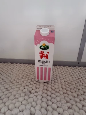Arla Rosa Mjölk dryck jordgubb Den är tom - En 1-liters förpackning Arla Rosa Mjölk dryck med smak av jordgubb. Kartongen är rosa och vit med en tecknad ko på framsidan och skruvkork på toppen. Perfekt för dig som gillar smaksatt mjölk och vill testa något annorlunda.