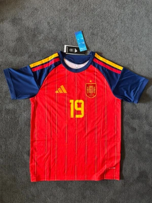 Spaniens VM 26/27 hemma Lamine Yamal 19 - Fotbollströja med Lamine Yamal på ryggen. Tröjan är helt ny med tagg kvar och i perfekt skick. Perfekt för dig som är supporter, samlar på fotbollströjor eller vill ha en snygg tröja till träning och vardag.                                                                      🔻Skickas inom 24 timmar.                                         Vid intresse eller frågor är det bara att skicka 👍