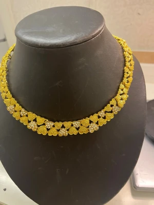 Guldhalsband med hjärtan och pärlor - Unikt halsband i guldfärg med små hjärtformade länkar och inslag av vita pärlor. Halsbandet har en elegant och detaljerad design som verkligen sticker ut. Perfekt för dig som vill ha något extra till din stil.