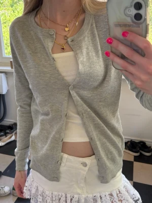 Ljusgrå basic kofta - Ljusgrå kofta i mjukt, tunt material med rund halsringning och knappar framtill. Enkel och stilren design som passar till det mesta. Långa ärmar och ribbade muddar vid ärmslut och nederkant. Perfekt att slänga över ett linne eller t-shirt.💕💕