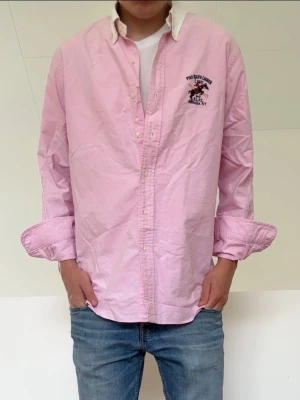 Rosa Ralph Lauren skjorta - Rosa Ralph Lauren skjorta i strl L men sitter som en M. Bra skick utan nåra defekter och hör gärna av er vid frågor elr funderingar!!