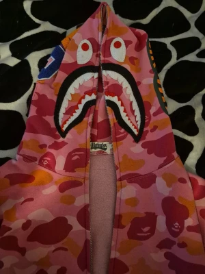 ÄKTA BAPE rosa camo shark hoodie - Säljer en äkta BAPE shark hoodie i rosa camo, säljer billigt för den har problem med dragkedjan och använder den inte tillräckligt för att fixa det