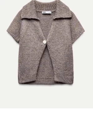 Beige stickad kofta från Zara - Kortärmad stickad kofta från Zara i beige nyans. Koftan har en bred krage, en dekorativ knapp framtill och ribbstickade kanter. Perfekt att slänga över en topp för en chill look.