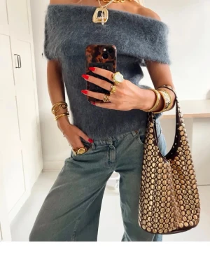 Mörkgrå offshoulder fluffig topp - Superfin mörkgrå offshoulder topp i fluffigt material. Toppen är axelbandslös och har en croppad passform som ger en trendig look. Perfekt att styla med jeans eller kjol för en cool vibe.