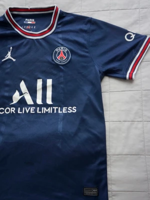 PSG | matchtröja b - Snygg blå PSG matchtröja med vita och röda detaljer från Jordan x Nike. Tröjan har klubbmärke på bröstet, Jumpman-logga och sponsortryck framtill. Tillverkad i lätt och ventilerande material, perfekt för fotboll eller träning. Helt ny och klassisk staple i fotbollsgarderober!