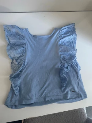 Ljusblå volangtopp Hampton Republic - Supersöt ljusblå topp från Hampton Republic med breda volangärmar i broderad spets. Toppen är ärmlös och har en mjuk bomullskänsla.💓