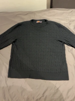 Kabelstickad Morris tröja  - Snygg svart kabelstickad tröja från Morris med rund halsringning och diskret broderad logga på bröstet. Tröjan har klassiskt flätmönster och är perfekt för dig som gillar stilrena och tidlösa plagg. Materialet känns mjukt och bekvämt. Den är i storlek S-M eftersom att den har krympt i tvätten men det står att den är i storlek XL på lappen, därför säljer jag den billigare. DM för mer information om tröjan eller intresse !!! (NYPRIS 1500kr)