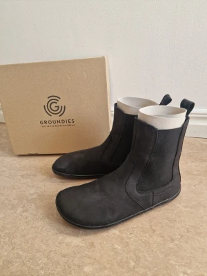 Chelsea barefoot boots from Groundies - Chelsea barefoot boots from Groundies. This is their barefoot+ model, for more room in the toe space. Soft suede and I really liked the thin sole. I have only tried them on and I realized I needed my actuall size. I didn't know the return was so expensive, so I'm giving it a try to sell them to someone who actually is a size 39. Just don't want to spend more than 35€ shipping them back 😅 I ordered a new pair in my actuall size and am very happy with them now 🥰 25,6 cm insole, 9,8 cm
