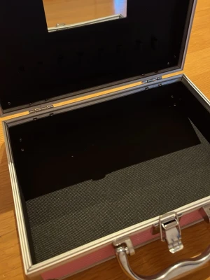 Rosa sminkväska med spegel - Snygg rosa sminkväska i hårdplast med silverfärgade metalldetaljer och handtag. Väskan har räfflad yta, spegel på insidan av locket och ett rymligt fack. Perfekt för att organisera smink eller småprylar.