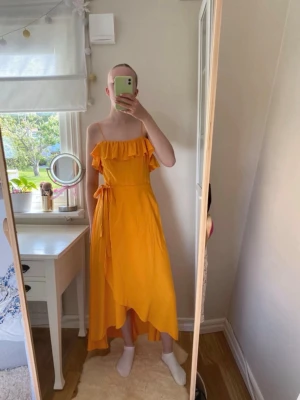 Gul omlottklänning med volang & other stories  - Säljer en lång gul klänning med omlott-design och volang upptill. Klänningen har smala axelband och knyt i midjan för en snygg passform. Perfekt för sommarens alla tillfällen och har en luftig känsla. Jättefin klänning från & Other Stories🧡 Inga synbara skavanker🥰 Jag på bilden är 172 cm lång med ganska långa ben, och på bilderna ser du hur lång den är på mig🥰 Bara att skriva om du undrar något😁