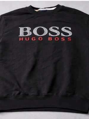 Svart sweatshirt från Hugo Boss - Svart sweatshirt från Hugo Boss med stort BOSS-tryck i vitt och grått samt röd HUGO BOSS-text på bröstet. Klassisk rund halsringning och ribbade muddar. Perfekt för en stilren och avslappnad look. storlek M men skulle säga att den passar S