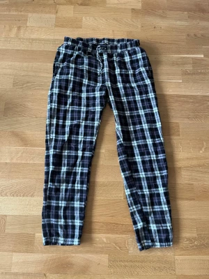 Rutiga pyjamasbyxor i bomull - Mysiga pyjamasbyxor med svart och vitt rutmönster. Byxorna har resår i midjan och dragsko för extra komfort. Tillverkade i mjukt bomullstyg, perfekta för slappa dagar hemma. Står att byxorna är i M, men skulle snarare säga att de passar bättre för S.