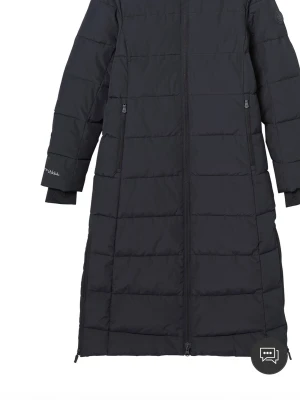 Svart lång dunjacka från Ellos - Snygg svart lång dunjacka från Ellos med dragkedja framtill och två fickor med dragkedja. Jackan har huva med dragsko och quiltad design. Perfekt för kalla vinterdagar och har en stilren look med diskret logga på ärmen.