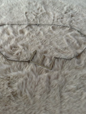 Silverfärgat halsband med bokstäver - Snyggt halsband i silverfärg med ett stort E. Kedjan är tunn och smidig, och bokstäverna ger ett personligt uttryck. Perfekt accessoar för dig som gillar enkel men unik stil.