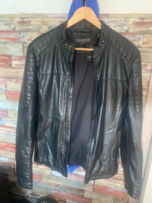 Svart jacka  från Pull&Bear - Snygg svart från Pull&Bear med quiltade detaljer på axlar och ärmar. Jackan har ståkrage med tryckknapp och dragkedja framtill. Perfekt för en cool och stilren look. Sitter taight 