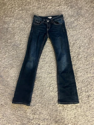Mörkblå bootcut jeans gina tricot - Snygga mörkblå bootcut jeans med kontrastsömmar och klassiska fem fickor. Jeansen har låg midja och är tillverkade i ett stretchigt denimtyg som sitter skönt. Perfekta för dig som gillar en tidlös och avslappnad stil.