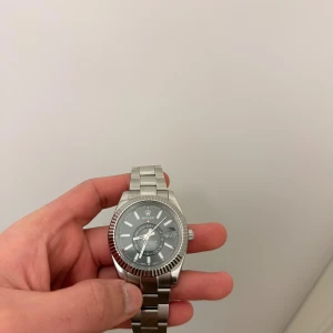 Herrklocka - Stilren silverfärgad klocka med metallarmband och rund urtavla. Klockan har tydliga markeringar, datumvisning och klassisk. Perfekt accessoar för dig som gillar exklusiv och tidlös design.