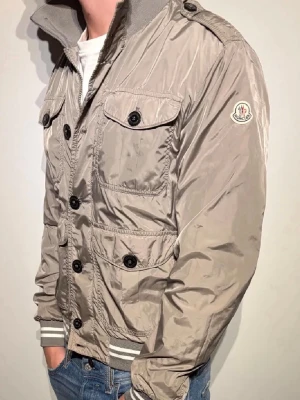 Moncler Jacka - Säljer min sjukt snygg sällsynta moncler vindjacka. Säljer den då den är lite för liten för mig. Den är i väldigt bra skick. Perfekt nu till våren. Den är storlek 3 vilket motsvarar M                  Priset är inte satt i sten