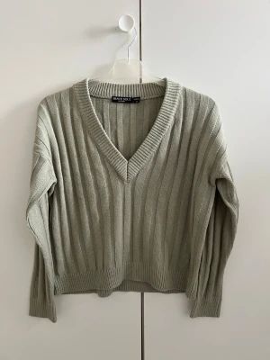 Ljusgrön stickad tröja från Brave Soul - Snygg ljusgrön stickad tröja från Brave Soul med djup V-ringning och breda ribbade ränder. Tröjan har långa ärmar och ribbade muddar vid ärmslut och nederkant. Perfekt för lager på lager och chill stil.