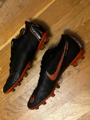 Nike Mercurial Vapor fotbollsskor - Säljer ett par svarta och orange Nike Mercurial Vapor i storlek 42. Inga synliga eller större skador på skorna så mycket bra skick på de! Skriv för frågor!
