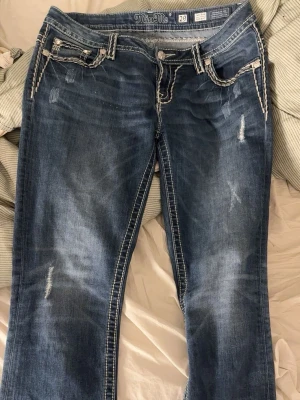 Blå Miss Me bootcut jeans - Snygga blå bootcut jeans från Miss Me med slitningar och kontrastsömmar. Jeansen har dekorativa fickor fram och bak och är i bra skick utan defekter! Skriv gärna om du har frågor!🥰