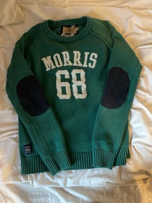Grön tröja med tryck från morris - Grön långärmad tröja från morris med vitt tryck på bröstet. Tröjan har rund hals, ribbade muddar och en avslappnad passform. Perfekt för en chill och stilren look.  Mycket bra skick, och i storlek S