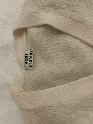 Vit kofta från Acne Studios - Säljer en stilren och mjuk vit kofta från Acne Studios. Koftan har v-ringning, långa ärmar och ribbade muddar. Materialet är tunt och fluffigt - men aldrig använd. Så söt och inga defekter!🥰