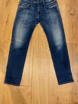 Blå Replay Hyperflex jeans -  33/32 Säljer ett par blå Replay Hyperflex jeans med snygg tvätt och slitningar. Klassisk femficksmodell med normal midja och raka ben. Jeansen har stretchigt material för extra komfort och passform. Perfekta för dig som vill ha en avslappnad men trendig look.