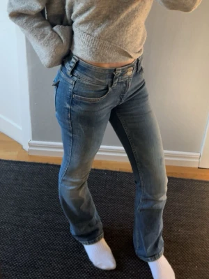 Blå bootcut jeans med låg midja - Snygga blå bootcut jeans med låg midja och klassiska fem fickor. Jeansen har en lätt tvättad look och raka ben som smalnar av lite nedtill. Perfekta för en avslappnad och trendig stil.är i väldigt bra skicka endast använda en gång men är tvättade!!