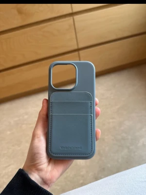 Blått mobilskal med kortfack (iphone 16 pro) - Snyggt blått mobilskal från Mobilefriend med två praktiska kortfack på baksidan. Skalet är gjort i ett mjukt material som känns skönt att hålla i och ger bra skydd till mobilen. Perfekt för dig som vill ha både stil och funktion i ett.