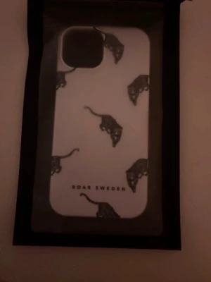 Roar Sweden Kitty Deluxe-Slim Case - Snyggt vitt mobilskal från Roar Sweden med svart leopardmönster. Skalet har en stilren design med flera leopard och är gjort i tåligt plastmaterial. Helt nytt och oanvänt mobilskal i perfekt skick. Passar modell iPhone 15. Inga repor eller synliga märken alls- direkt ur förpackningen. Pris kan diskuteras!!!