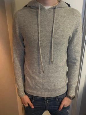Ljusgrå merinoull hoodie - Schysst grå 100% merinoull hoodie. Köpt online och märke okänt. Lite kort på modellen, strlk M. Köpt för 700kr. Gott skick. Pris går att diskutera.