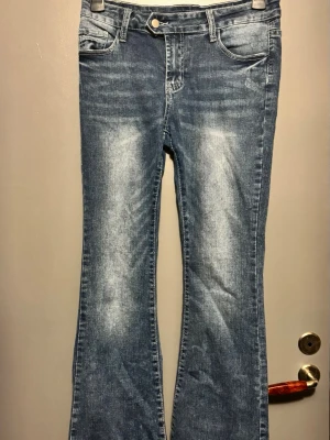 Blå bootcut jeans från Shein - Snygga blå bootcut jeans från Shein med klassisk fick modell och ljusa slitningar framtill. Jeansen är stretchiga för bekvämare känsla. Perfekta för en avslappnad och trendig look.