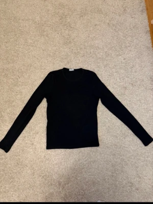 Svart ribbstickad tröja - En enkel och stilren svart ribbstickad tröja med rund hals och långa ärmar. 