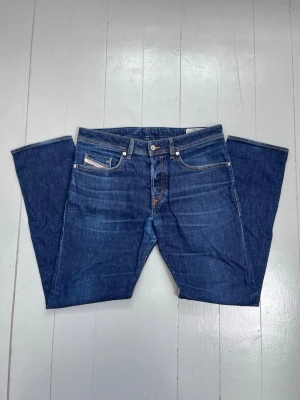 Mörkblå jeans från Diesel - Snygga mörkblå jeans från Diesel med klassisk femficksmodell och raka ben. Jeansen har kontrastsömmar och en läderpatch med Diesel-logga bak i midjan. Tillverkade i slitstark denim som ger en cool och tidlös look.