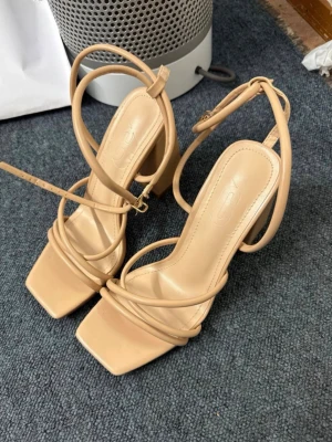 Beige sandaletter med blockklack - Snygga sandaletter i beige med fyrkantig tå, tunna remmar och justerbar ankelrem. Skorna har en stabil blockklack och minimalistisk design som passar till många olika outfits. Tillverkade i konstläder för en stilren look. I ny skick har ej använt dem 