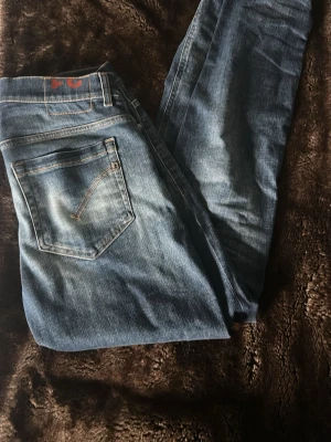 Dondup Jeans - Säljer ett par blå jeans från dondup med slitningar och tvättade detaljer. Klassisk femficksmodell med smal passform och orangea sömmar. Perfekta för en avslappnad och trendig look. Materialet är denim i bomull.