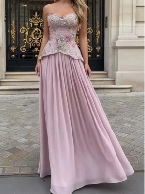 Ljusrosa långklänning med korsett blommor - Elegant ljusrosa långklänning från Reinee Couture med blommiga broderier och pärlor på överdelen. Klänningen har en axelbandslös corsettopp och ett långt, svepande kjolparti i mjukt tyg. Perfekt för speciella tillfällen där du vill sticka ut.