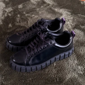 Eytys Svarta leather sneakers - Säljer ett par svarta chunky med grov sula och lila hälflik. Skorna har en clean design med släta partier i läderimitation och matchande svarta skosnören. Perfekta för dig som gillar streetwear och vill sticka ut lite extra.