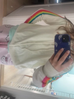 Vit hoodie med regnbågsränder - Säljer en vit hoodie med rengbågigt mönster på armarna 