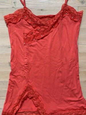 Topp med spets och paljetter - Topp från märket Tessie i storlek s/m. Vanlig eller unik? Otroligt fin hur som med färgen, spetsen, passformen, paljetterna, osymetriska i botten. Strechtigt material som följer kroppen. (Färgen är aprikos enligt mig, skulle kunna säga orange och röd också)