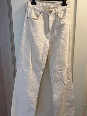 Vita raka jeans från Monki - Säljer ett par vita jeans från Monki med rak passform och hög midja. Klassisk femficksmodell med knapp och dragkedja framtill. Säljer pågrund av att dessa är för små, offwhite 