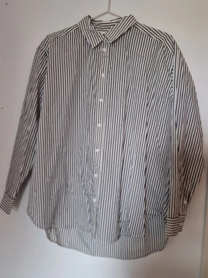 Skjorta - Skjortan har lång ärm, knappar framtill och en avslappnad passform. Perfekt till jeans eller kjol för en clean look.