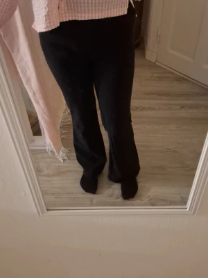 Svarta utsvängda kostymbyxor - Snygga svarta kostymbyxor med utsvängda ben och hög midja. Byxorna har en klassisk siluett och är tillverkade i ett mjukt, följsamt tyg som ger en clean look. Perfekta att matcha med skjorta eller crop top.