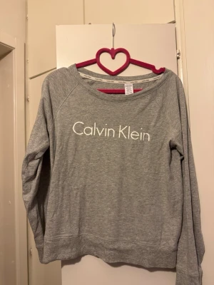 Calvin Klein tröja grå strl XS - Calvin Klein tröja med tryck av text i vitt.