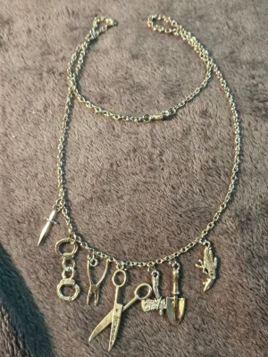 Läckert halsband med berlocker horror movies tema  - Unikt halsband i silvermetall horror movies tema, flera detaljerade berlocker som sax, handbojor, tång, dolk, spade, yxa. Kedjan är kraftig 49cm lång, och berlockerna ger en cool och edgy känsla. Perfekt för dig som gillar statement-smycken och vill sticka ut.