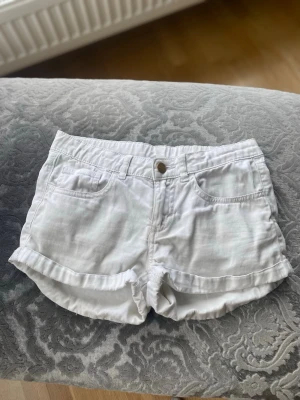 Vita shorts med uppvikta ben - Snygga vita shorts med uppvikta ben och klassisk femficksdesign. De har knapp och dragkedja framtill samt bälteshällor i midjan. Perfekta för varma dagar och enkla att matcha med allt. Fint skick!!🌟