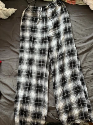 Rutiga mjukisbyxor från H&M Divided - Svarta och vita rutiga mjukisbyxor från H&M Divided. Byxorna har resår i midjan med dragsko och är tillverkade i ett mjukt och lätt material. Perfekta för en avslappnad och chill stil. Använda väldigt fåtal gånger.