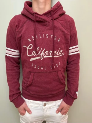 Vinröd hoodie från Hollister - Snygg vinröd vintage hoodie!! Passar perfekt till chill och sköna outfits. Märke:Hollister. Size M men passar även  S!! Skick 9/10!! Model 176cm/väger 64kg